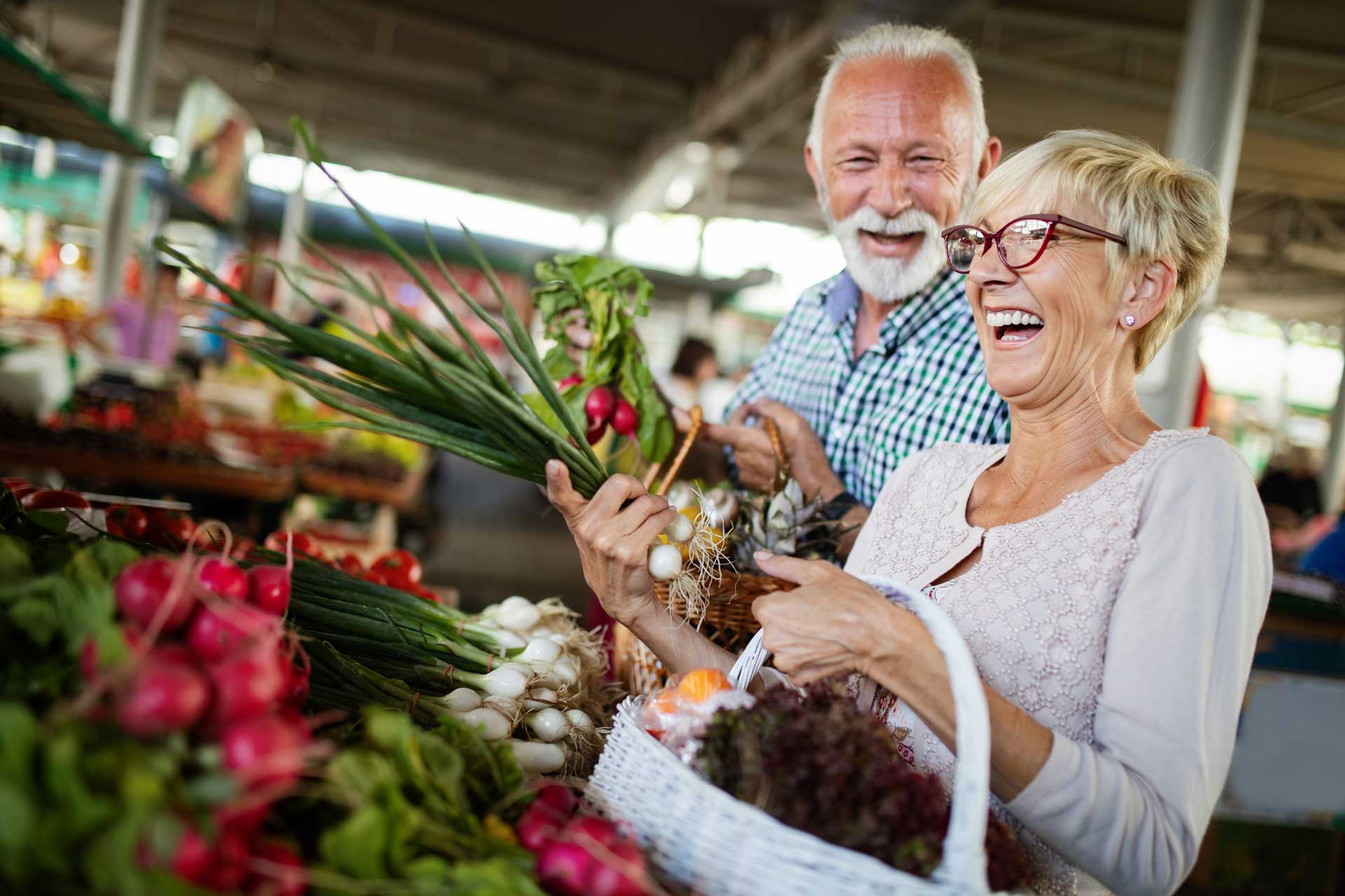 Older couple laughing together at the grocery store.
